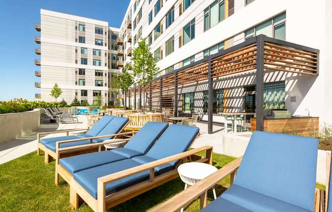 A sunny day at the rooftop pool with blue lounge chairs and a wooden pergola.