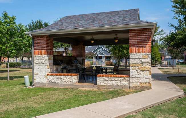 a brick and stone pavilion with a table and chairs under it