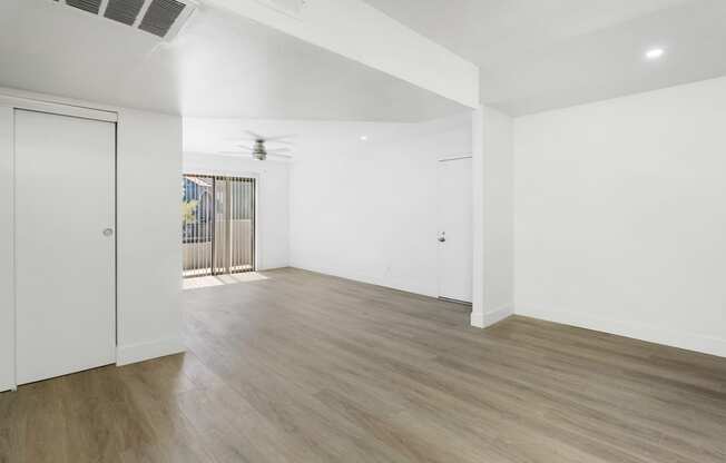 an empty living room with white walls and wood flooring