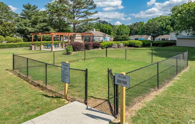 a fenced in park with a playground and a picnic area