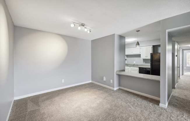 the living room and kitchen of an apartment with gray walls and carpet  at Governors House, Huntsville