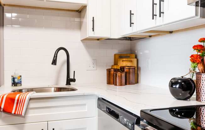 a white kitchen with white cabinets and black appliances and a sink