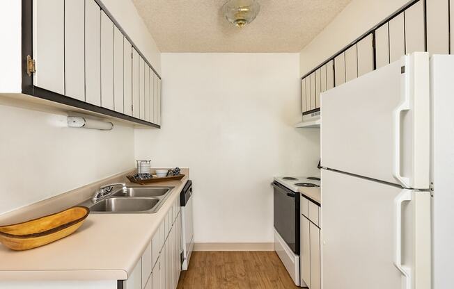 Aurora, CO Apartments – Ivy Crossing – A kitchen with a white refrigerator and a wooden bowl on the counter.