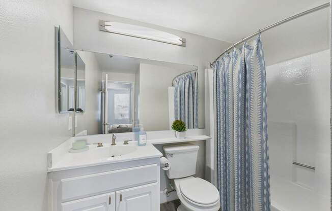 A white bathroom with a sink, toilet, and shower.