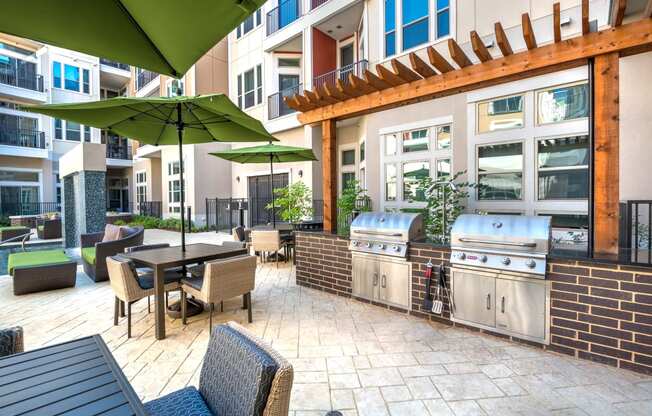 a patio with a grill and tables with umbrellas