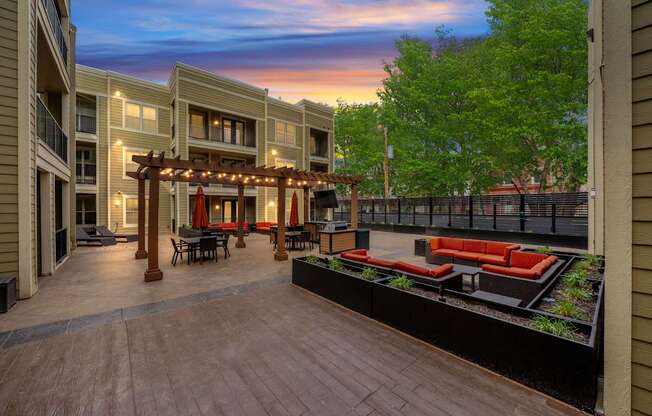 Spacious courtyard at West 39th Street Apartments with multiple seating areas, pergola, and outdoor TV.