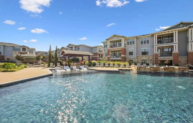 A swimming pool in front of apartment buildings on a sunny day.