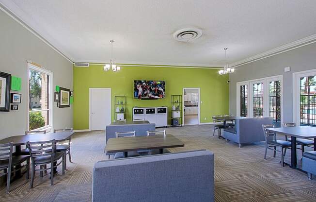 a common room with tables and chairs and a television on the wall