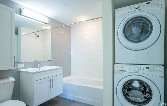 A white washing machine sits next to a white bathtub in a bathroom at 603 Concord Apartments, Cambridge