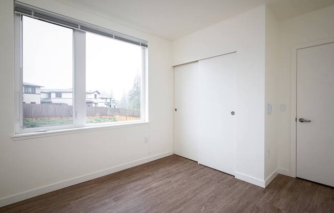 an empty bedroom with a large window and a door