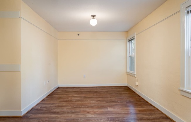 an empty room with a hardwood floor and two windows