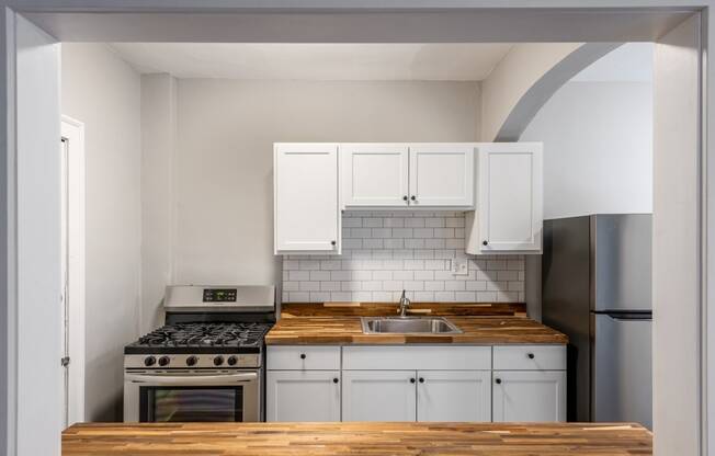 a kitchen with white cabinets and a stove and a sink