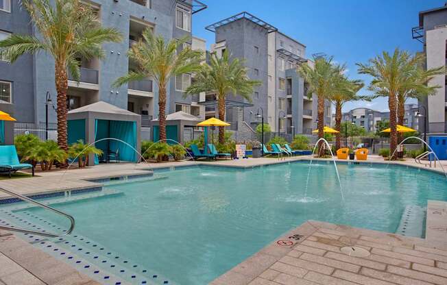 A pool surrounded by palm trees and lounge chairs.