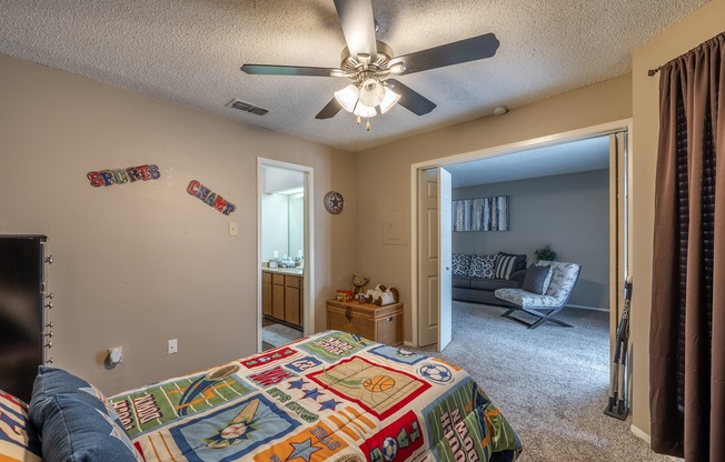 A bedroom with a bed, a ceiling fan, and a chair.
