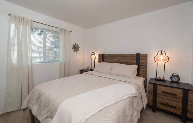 A bedroom with a large bed and two lamps on either side of the bed at Sierra Glen Apartments, California, 95621
