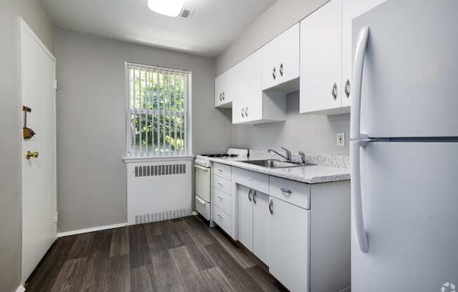 an empty kitchen with white cabinets and a window at Hampton Gardens, Missouri, 63139