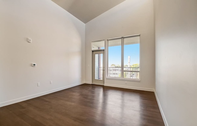 A room with a wooden floor and a sliding glass door leading to a balcony.