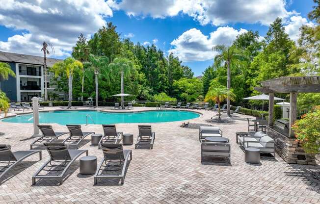 a swimming pool with tanning chairs at Verano apartments