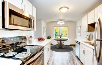 a kitchen with white cabinets and stainless steel appliances and a table