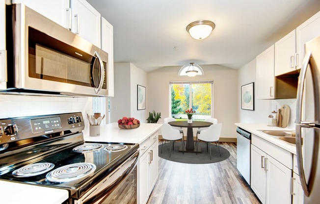 a kitchen with white cabinets and stainless steel appliances and a table