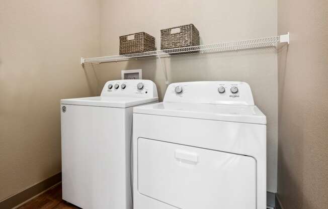 Two white front loading washing machines in a laundry room.