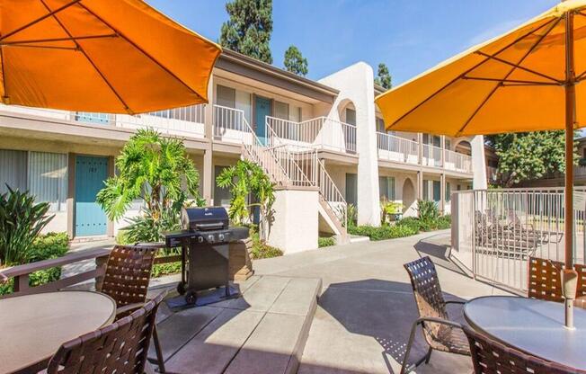 a patio with chairs and umbrellas and a grill