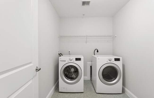 Two white front loading washing machines in a small laundry room.