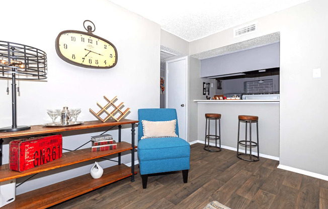 A blue chair sits in a room with a clock on the wall.