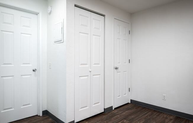 an empty room with three white doors and a wooden floor