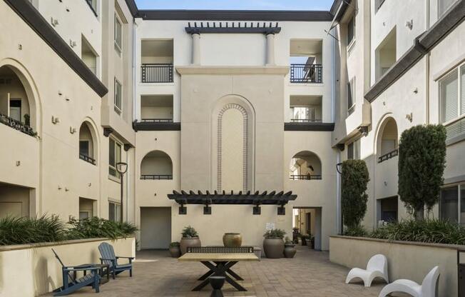 a courtyard with a table and chairs in an apartment building