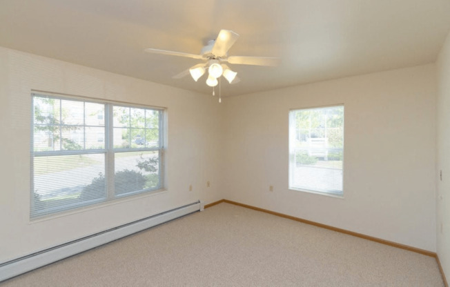 a bedroom with a ceiling fan and two windows