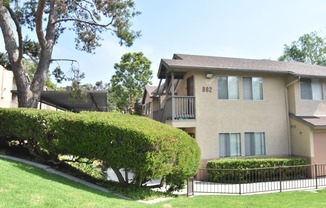 a large apartment building with a lawn and trees in front of it