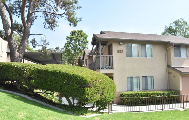a large apartment building with a lawn and trees in front of it