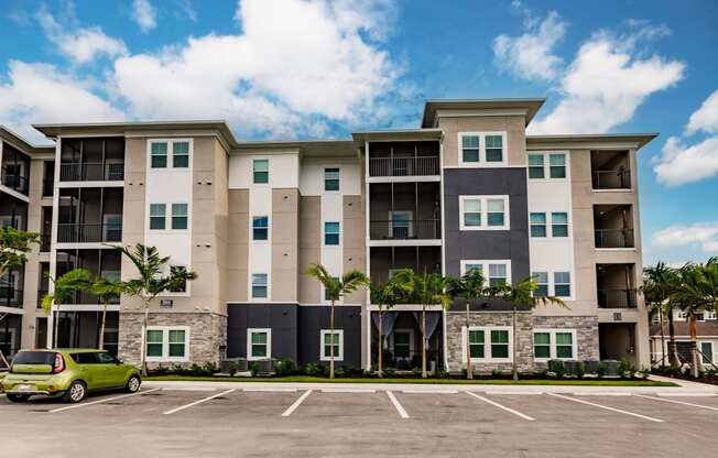 an apartment building with a parking lot and a green car in front of it