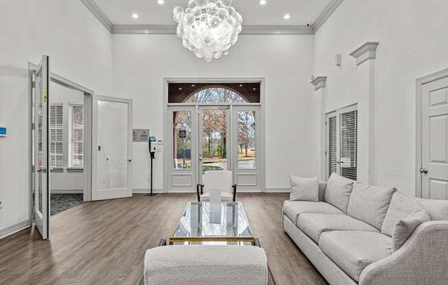 A modern living room with a glass coffee table and a grey sofa.