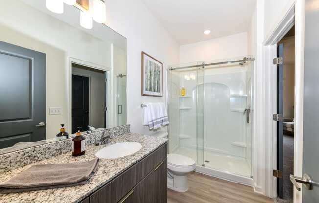 Model bathroom with wide, granite vanity and walk-in shower at The Station at Brighton apartments