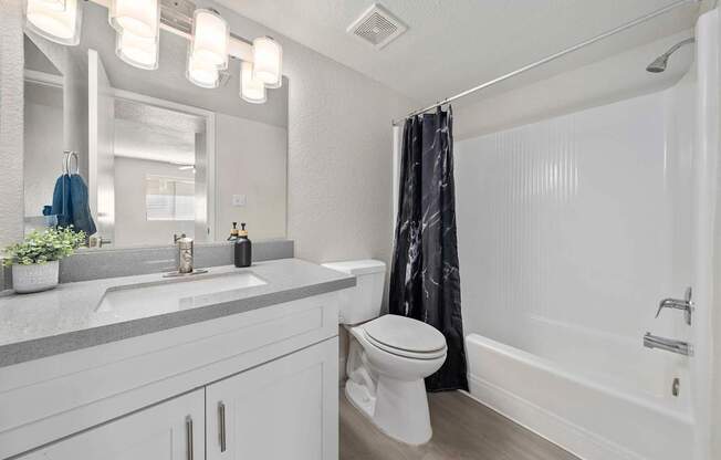 A white bathroom with a toilet, sink, and shower.