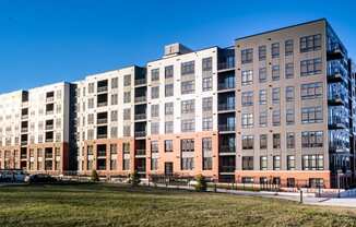 a large apartment building with many windows and a grass field