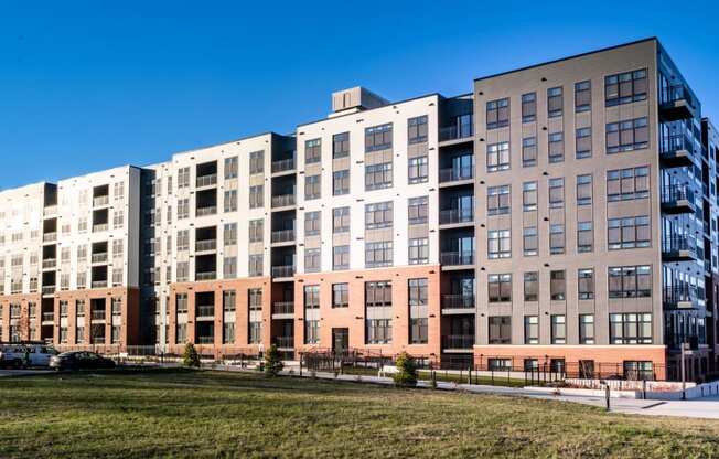 a large apartment building with many windows and a grass field