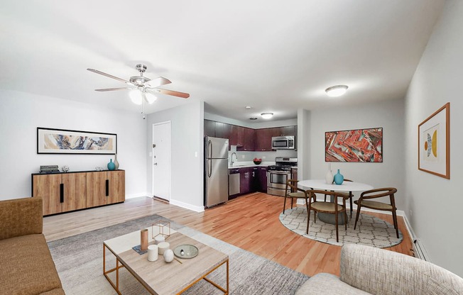 a living room with a couch a table and a chair and a kitchen with a stove and