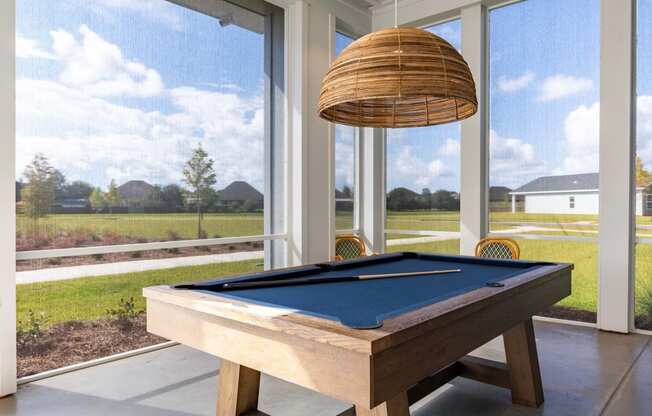 a pool table in a screened in porch with a lamp