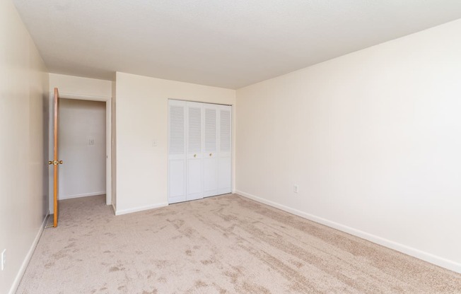 a bedroom with white walls and carpet with extra storage space