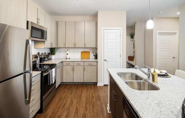 Kitchen with granite countertops, stainless steel appliances, subway tile backsplash and wood-designed flooring at The Alexandria in Madison, AL