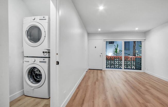 a white laundry room with a washing machine and a door to a balcony