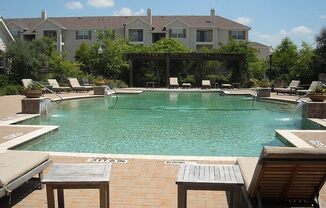 a swimming pool with chairs and a house in the background