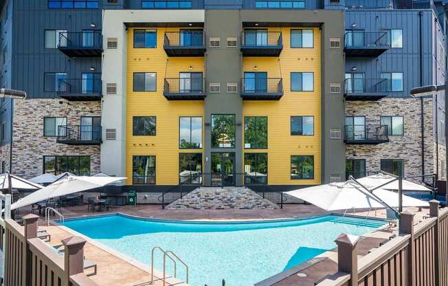 a swimming pool at an apartment building with a pool and umbrellas. Circle Pines, MN Lexington Lofts