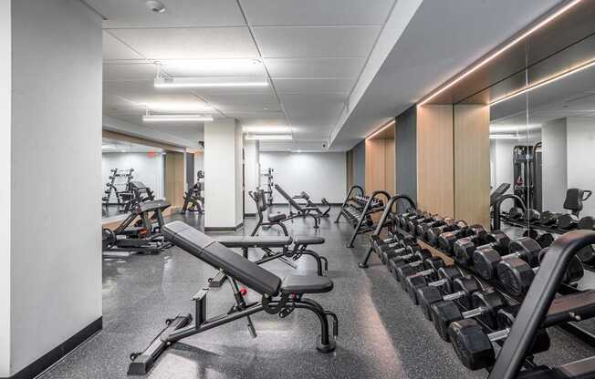 A gym with a variety of equipment including dumbbells and weight machines.