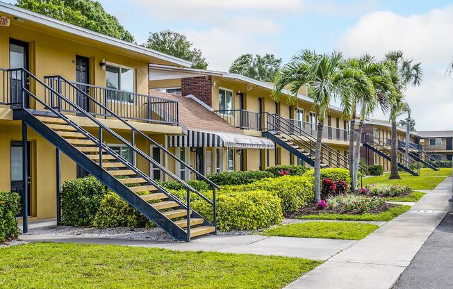 a row of yellow houses with stairs and palm trees