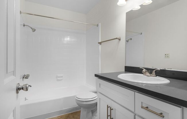 A white bathroom with a toilet, sink, and bathtub.