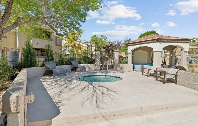 a backyard with a pool and patio with chairs and a fountain